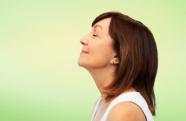 Image showing profile of smiling senior woman over lime green