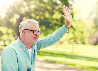 Image showing happy senior man waving hand at summer park