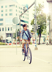 Image showing young hipster man with bag riding fixed gear bike