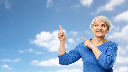 Image showing smiling senior woman pointing fingers to sky