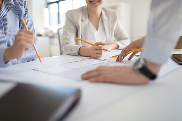 Image showing close up of architects with blueprint at office