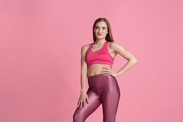 Image showing Beautiful young female athlete practicing on pink studio background, monochrome portrait