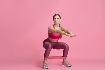 Image showing Beautiful young female athlete practicing on pink studio background, monochrome portrait