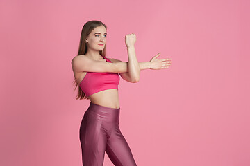 Image showing Beautiful young female athlete practicing on pink studio background, monochrome portrait