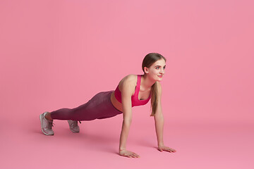 Image showing Beautiful young female athlete practicing on pink studio background, monochrome portrait