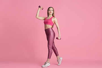 Image showing Beautiful young female athlete practicing on pink studio background, monochrome portrait