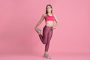 Image showing Beautiful young female athlete practicing on pink studio background, monochrome portrait