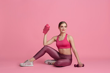 Image showing Beautiful young female athlete practicing on pink studio background, monochrome portrait