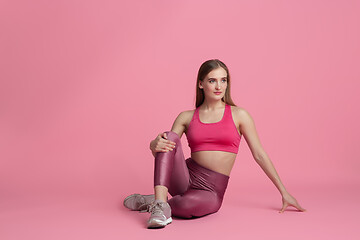 Image showing Beautiful young female athlete practicing on pink studio background, monochrome portrait