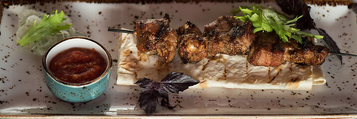 Image showing shashlik on a barbecue skewer with sauce