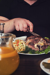 Image showing Man eats tasty dish of pork shank