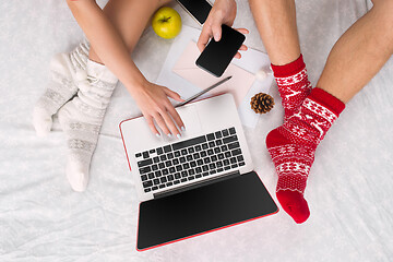 Image showing caucasian couple at home using internet technology LLaptop and phone for people sitting on the floor