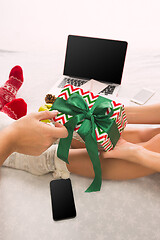 Image showing caucasian couple at home with gift. Laptop and phone for people sitting on the floor