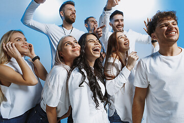 Image showing Group of cheerful joyful young people standing and celebrating together over blue background