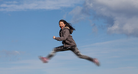 Image showing Cute girl running jumping at the on a field in the summer