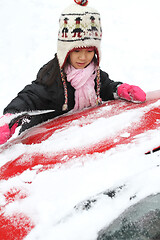 Image showing Portrait of a young cute girl looking at the camera romoving sno