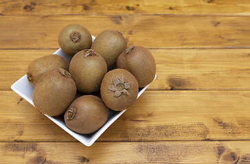 Image showing Selection of hairy-skinned kiwifruit in a bowl on a table