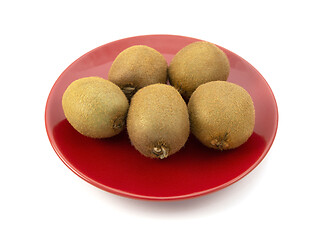 Image showing Five fresh whole kiwi fruits on a red plate