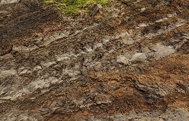 Image showing A cut of soil with rocks and red soil