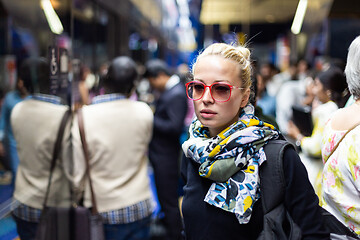 Image showing Young woman wearing colorful scarf waiting on the platform of a urban metro station for train to arrive. Public transport