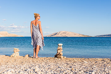 Image showing Happy carefree woman enjoying late afternoon walk on white pabbled beach on Pag island, Croatia