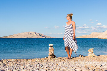 Image showing Happy carefree woman enjoying late afternoon walk on white pabbled beach on Pag island, Croatia