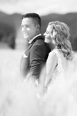 Image showing Newlyweds hugging tenderly in wheat field somewhere in Slovenian countryside. Caucasian happy romantic young couple celebrating their marriage