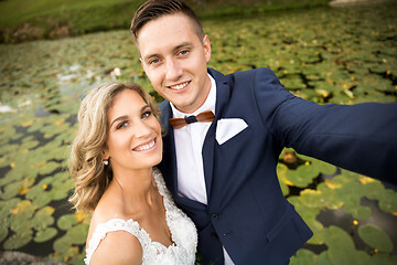 Image showing Wedding selfie. Bride and groom hugging tenderly posing during photo shooting in park.