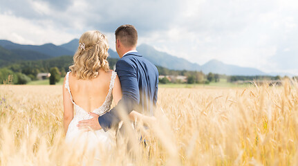 Image showing Rear view of groom huging bride tenderly in wheat field somewhere in Slovenian countryside.