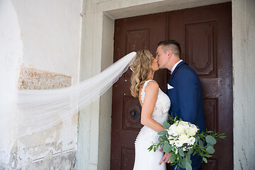 Image showing The Kiss. Bride and groom kisses tenderly in front of church portal.