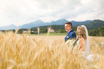 Image showing Bride hugs groom tenderly in wheat field somewhere in Slovenian countryside.