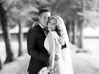 Image showing Bride and groom hugging tenderly posing during photo shooting in park.