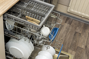 Image showing Clean dishes, cups, spoons and forks in a dishwasher at home kitchen