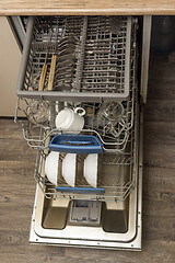 Image showing Dishwasher with clean plates, cups, spoons and forks in kitchen at home