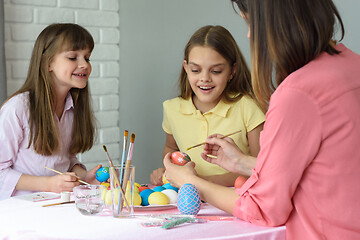 Image showing Mom with two daughters paint eggs for Easter