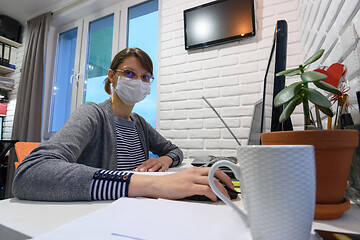 Image showing A sick quarantined girl in self-isolation at home works remotely in a computer