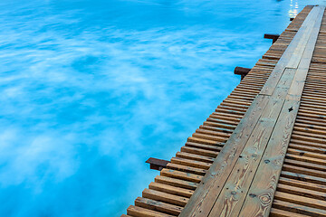 Image showing The bridge goes into the distance on the right side, on the left a water surface shot with a long exposure