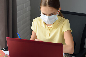 Image showing Girl in medical mask studies online at home