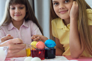 Image showing Coloring Easter eggs in glasses with liquid dye, the girl looked in the frame