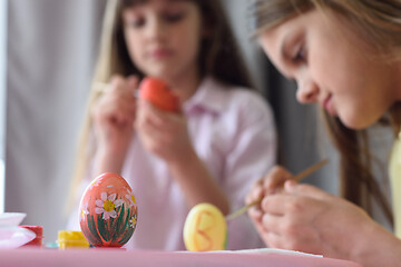 Image showing Children paint Easter eggs, focus on the egg in front of them