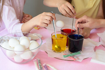 Image showing Children interfere with a solution with food coloring in glasses to paint Easter eggs