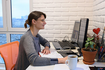 Image showing Happy girl working remotely at home at a personal computer