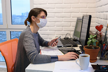 Image showing A sick girl in a medical mask in self-isolation works remotely