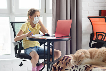 Image showing A sick girl in self-isolation sits at a table and does homework online