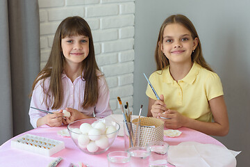 Image showing Children are preparing to paint Easter eggs while sitting at a table in a home environment.