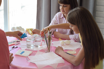 Image showing Children pour dye for coloring eggs in glasses with water