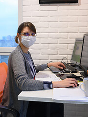 Image showing The sick quarantined girl works at the computer, looked into the frame