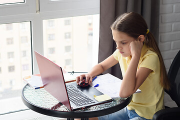 Image showing Girl thoughtfully doing homework, sitting at a table by the window