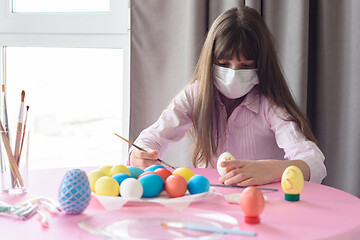 Image showing Quarantine-infected girl alone paints Easter eggs