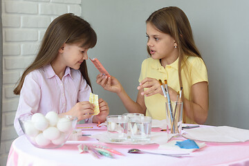 Image showing A girl shows the other girl the contents of a bag of food coloring